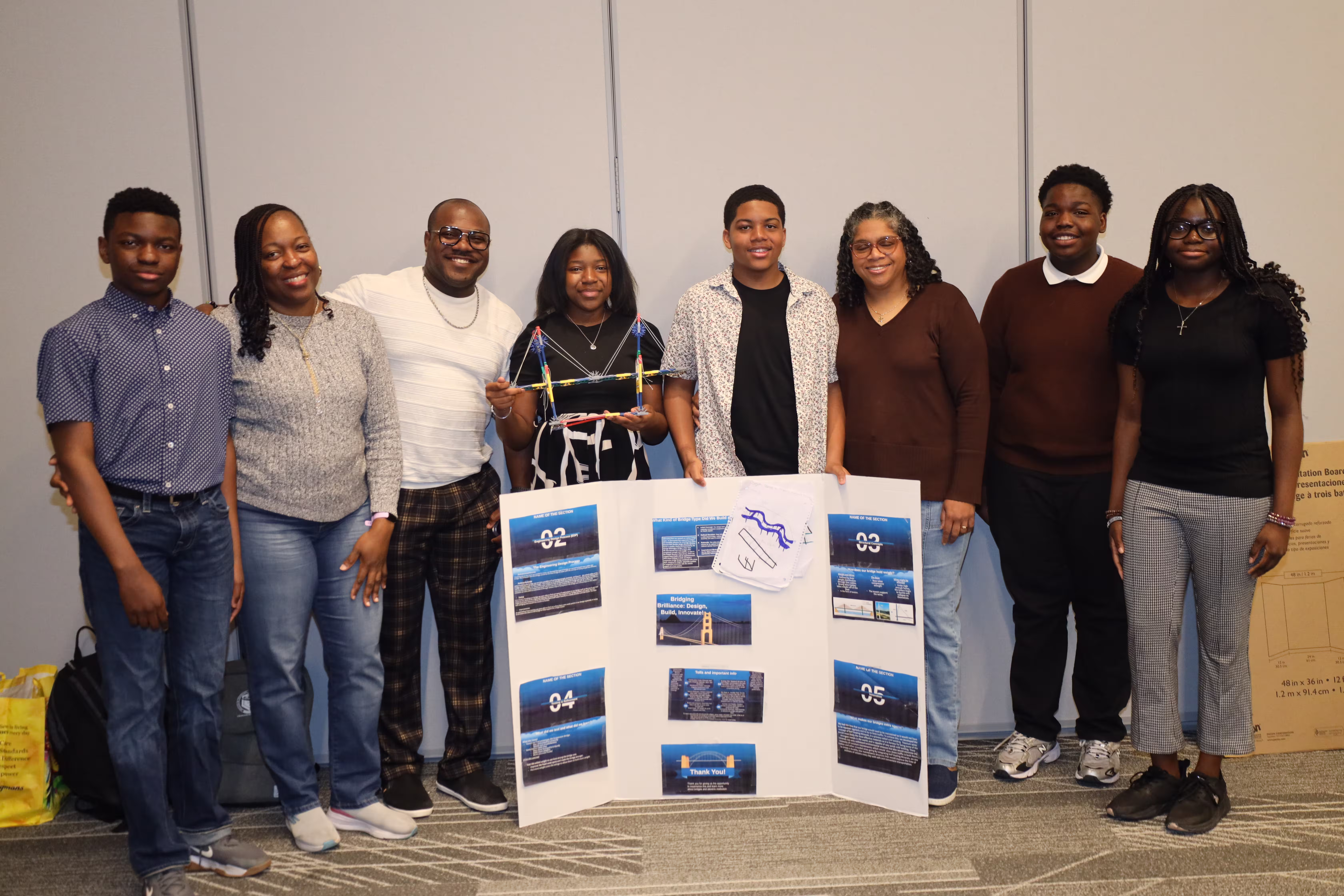Explore scholars presenting a bridge prototype and research poster at the STEM Expo