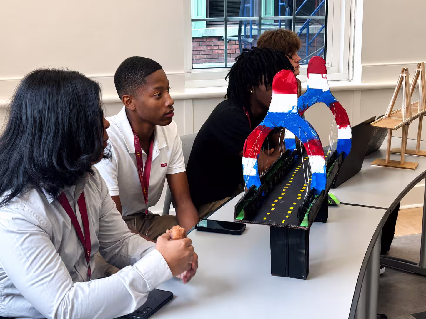 A Pathway student examining a bridge prototype during a design critique